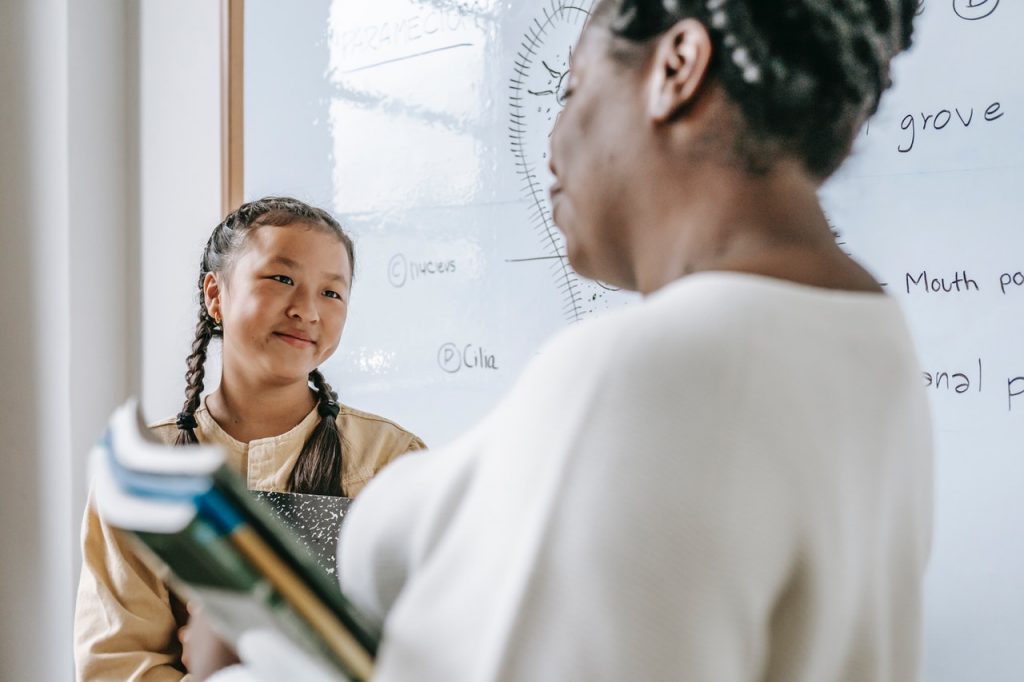 An educator incorporates emotional intelligence as she  teaches her smiling student 